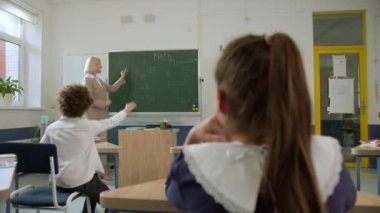 Elementary school class, children communicate with the teacher, answering various questions.