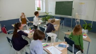 Elementary school class, children communicate with the teacher, answering various questions.