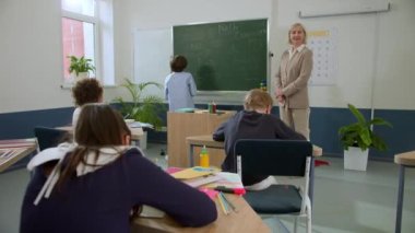 Elementary school class, children communicate with the teacher, answering various questions.