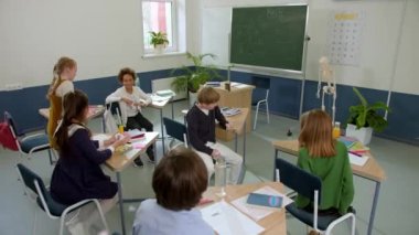 Elementary school class, children communicate with the teacher, answering various questions.