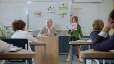 İlköğretim sınıfı, çocuklar öğretmenle iletişim kurar, çeşitli soruları cevaplarlar..