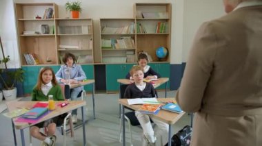 Elementary school class, children communicate with the teacher, answering various questions.