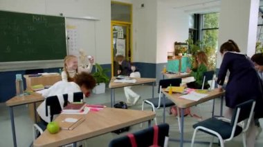 Elementary school class, children communicate with the teacher, answering various questions.