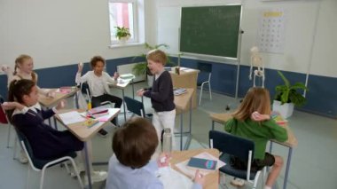 Elementary school class, children communicate with the teacher, answering various questions.