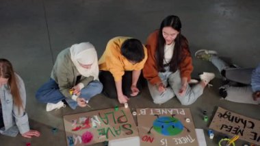 Bir grup genç, çevre kirliliğini protesto etmek için posterler çiziyor..