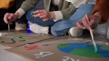 A group of young people draw posters and protest against environmental pollution.