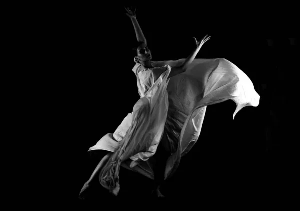 Dancer in a white robe.Beautiful lyrical dancer on a black background.