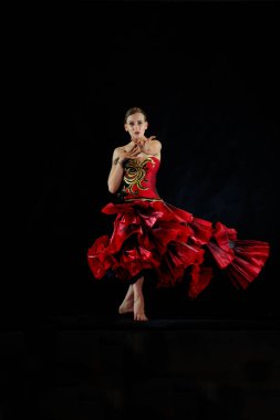 Siyah arka planda kırmızı elbiseli güzel bir dansçı..