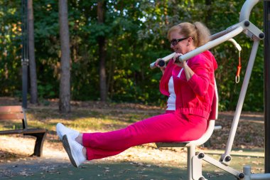 Parkta spor salonunda egzersiz yapan bir kadın. Orta yaşlı bir bayan.