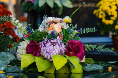 Azizler Günü 'nde mezarlıkta çiçekler ve mumlar. Mezarlıktaki ölü birinin mezarında renkli çiçekler.. 