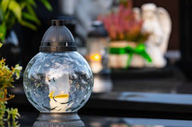 Mezarlıktaki bir mezarda yanan bir mumla fener.