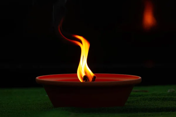 Close up of burning candle on green grass with black background, selective focus