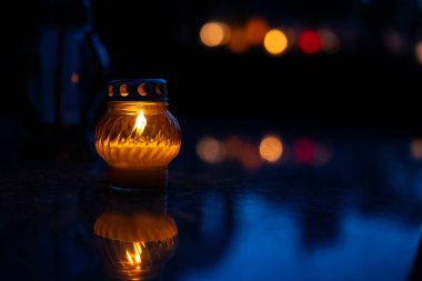 Gece mezarlıkta fener, arka planda çiçeklerle. Gece mezarlıkta mum ışığı. Seçici odak.