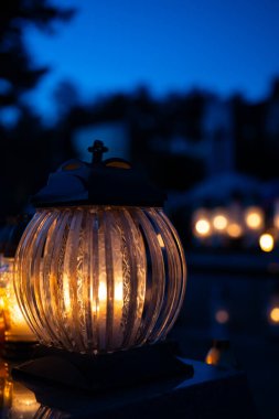 Gece mezarlıkta fener, arka planda çiçeklerle. Gece mezarlıkta mum ışığı. Seçici odak.
