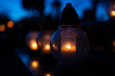 Geceleri mezarlıkta mumlar yanıyor. Seçici odaklanma. Geceleri mezarlıkta mumlar. Derin tarlalar. Geceleri mezarlıkta fenerler. Azizler Günü.