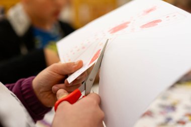 Çocuğun ellerine yakın çekim makasla bir parça kağıt kesme