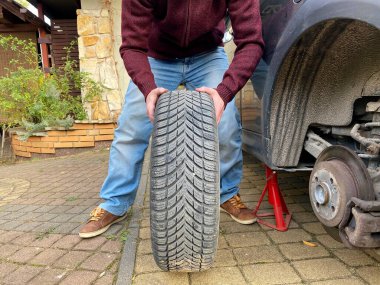 Lastik değiştirme. Bir arabanın tekerleğini sürgülemek. Mevsimlik lastik değişimi. Kaldırın. Krikonun üstündeki araba. Araba servisi.. 