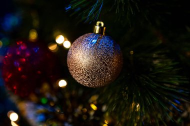 yakın - bir noel ağacının önünde bir top ve noel süslemeleri, bulanık ışıklar.