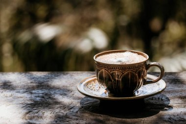 Eski ahşap masada, fincanda sıcak latte kahve..