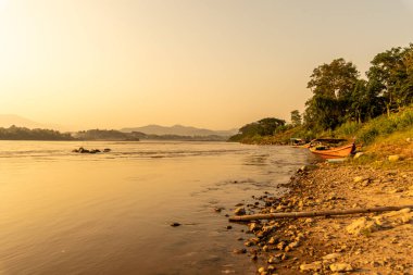 Mekong Nehri 'nin çevresi dağlarla çevrili ve gün batımında sarı güneş ışınlarıyla çevrili. Chiang Khong, Chiang Rai, Kuzey Tayland.