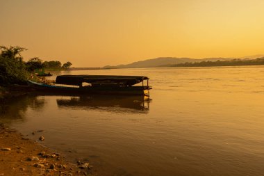 Mekong Nehri 'nin çevresi dağlarla çevrili ve gün batımında sarı güneş ışınlarıyla çevrili. Chiang Khong, Chiang Rai, Kuzey Tayland.