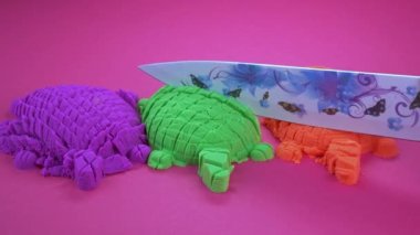 Renkli bir arka planda bıçakla Kinetik kum kesimi. ASMR sesleri.