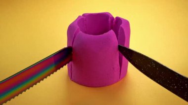 Çok renkli bir arka planda, kinetik kumu bıçakla kesmek..