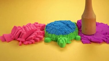 Çok renkli bir arka planda, kinetik kumu bıçakla kesmek..