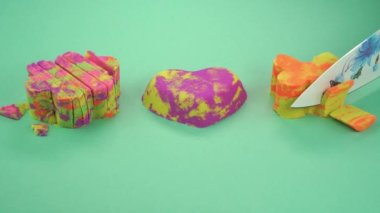 Çok renkli bir arka planda, kinetik kumu bıçakla kesmek..