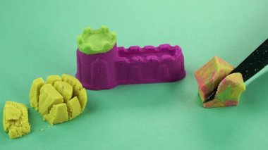 Çok renkli bir arka planda, kinetik kumu bıçakla kesmek..