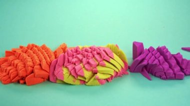 Çok renkli bir arka planda, kinetik kumu bıçakla kesmek..