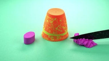 Çok renkli bir arka planda, kinetik kumu bıçakla kesmek..