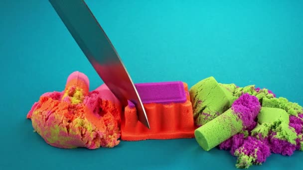 Çok Renkli Bir Arka Planda Kinetik Kumu Bıçakla Kesmek — Stok video