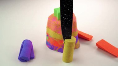 Beyaz arka planda bir bıçakla kinetik kumu kesiyor..