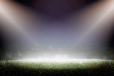 Yeşil çimenler ve bulanık bokeh. Karanlık doğa geçmişi. Sahne ışıkları çimlerin üzerindeki yeri aydınlatıyor. Futbol.