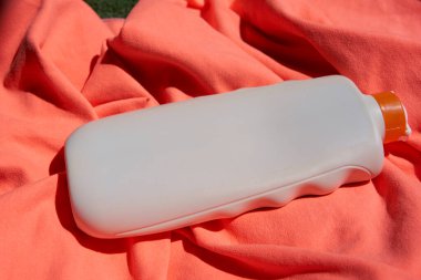 Turuncu havluyla bir şişe güneş kremi yakın plan.