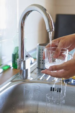 Eller mutfakta cam bardakları sünger ve deterjanla ovalıyor.