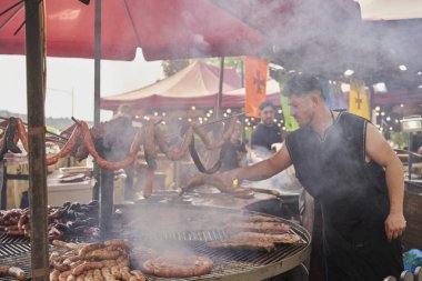 Kalabalık bir ortaçağ pazarında büyük bir ızgarada cızırdayan etler eski aşçılık geleneklerinin özünü yakalıyor.