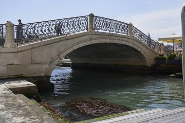 Resimli Venedik köprüsü berrak gökyüzünün altında sakin kanal sularını geçerek bu ikonik İtalyan şehrinin dingin güzelliğini ve tarihi cazibesini yakalıyor.
