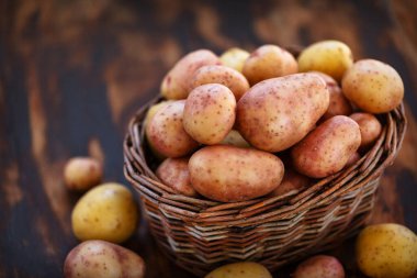 Tahta arka plandaki sepette çiğ patates.
