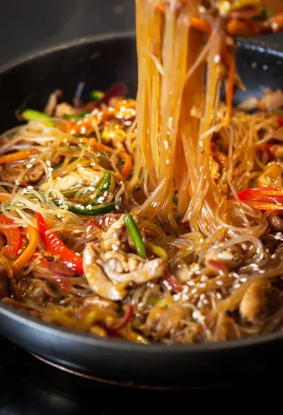 Tavada tavuk ve sebzeli Asya usulü kızarmış erişte.