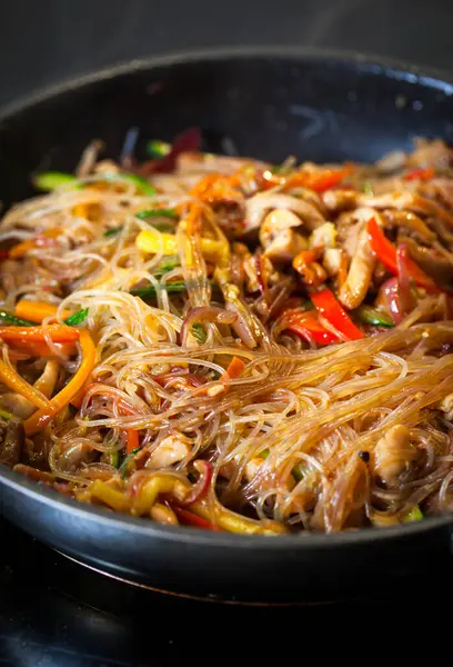 Tavada tavuk ve sebzeli Asya usulü kızarmış erişte.