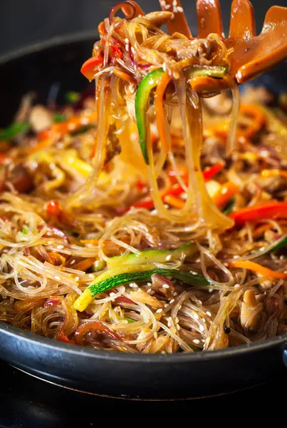 Tavada tavuk ve sebzeli Asya usulü kızarmış erişte.