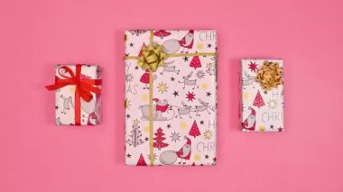 Pastel pembe arka planda Noel hediyelerini değiştiriyorum. Noel tebrik kartı. Hareketi durdur. Düz yatıyordu