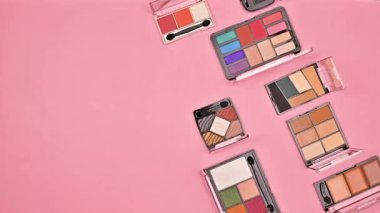 Makyaj gölgeleri pastel pembe arka planda hareket eder. Düz yatıyordu. Hareketi durdur