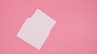 Zarflı kağıt ve Noel hediyesi pastel pembe arka planda görünüyor. Düz yatıyordu. Hareketi durdur