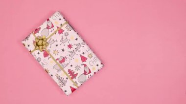Noel hediyesi, pastel pembe arka planda daireler çiziyor. Düz yatıyordu. Uzayı kopyala Hareketi durdur
