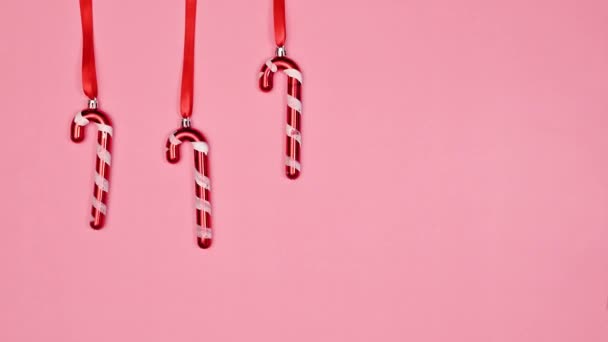 可爱的圣诞糖果手杖在彩带上摇曳 衬托着柔和的粉色背景 平躺在床上停止运动 — 图库视频影像