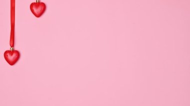 Hanging hearts for Valentine's day on pastel pink background. Flat lay. Stop motion