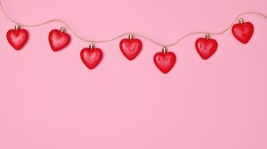 Valentine's day garland with hearts on pastel pink background with copy space. Valentine greeting card. Stop motion
